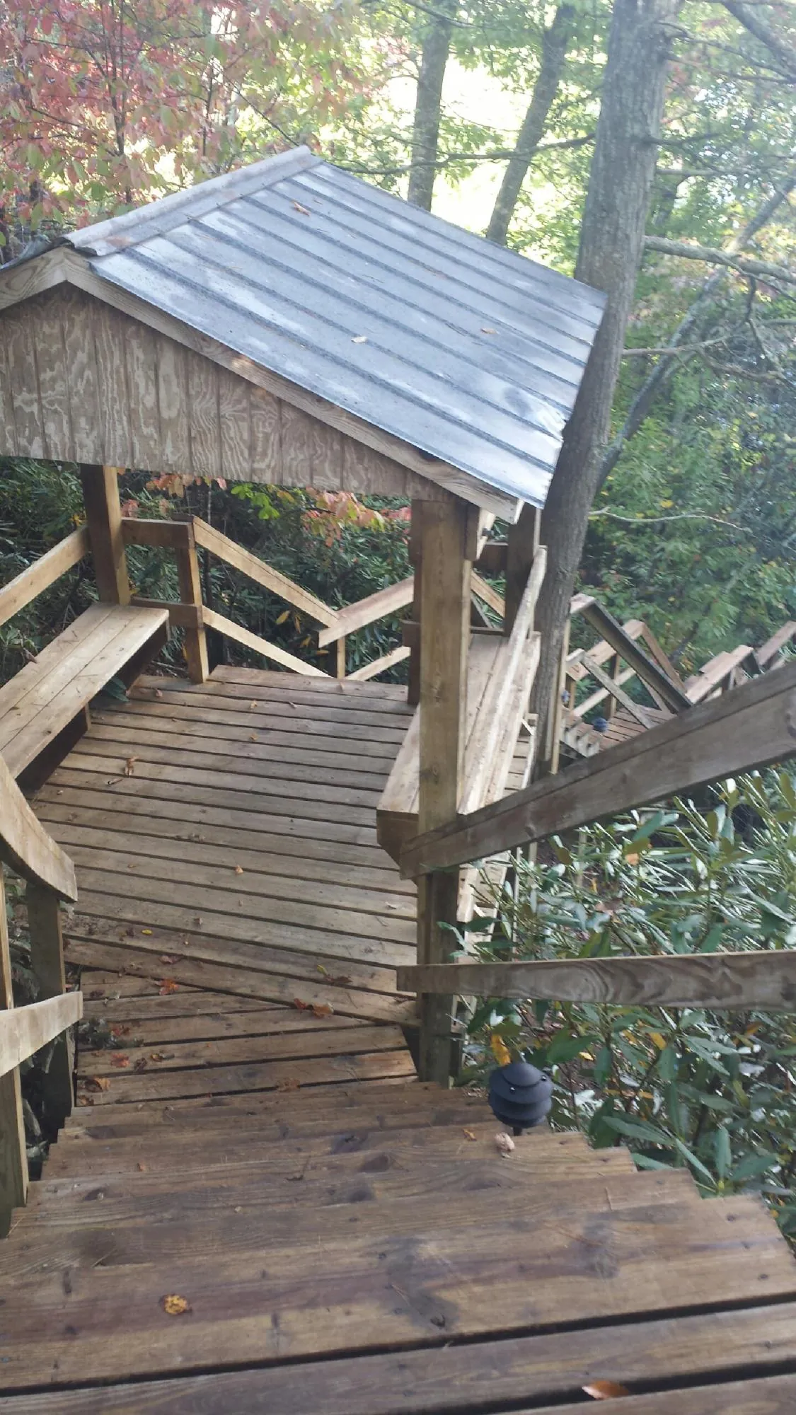 Metal roofed shelter over wooden steps on a wooded walkway — Skylight Repair & Installation work by our crew in Mattaponi