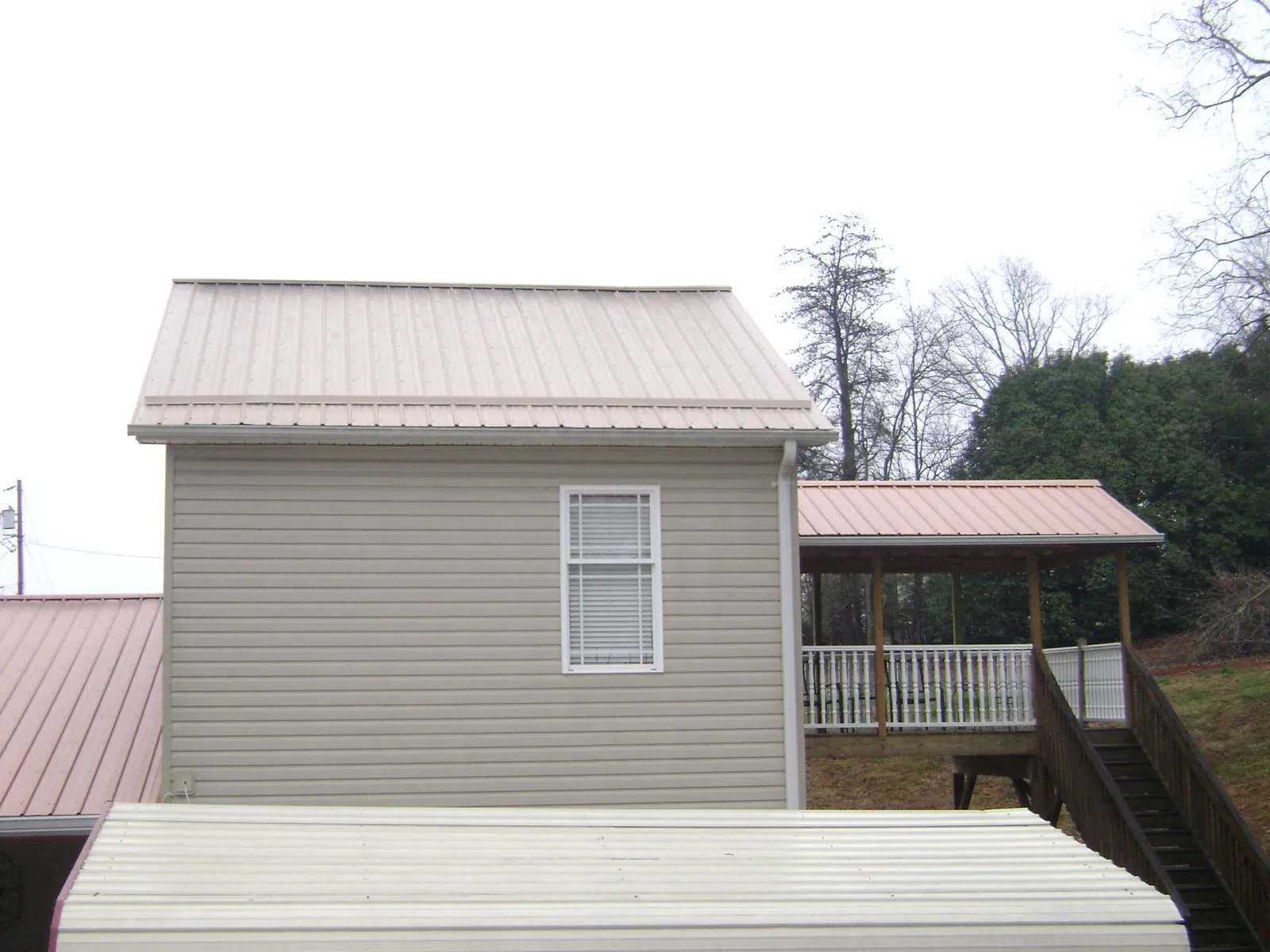 Tan metal roofs on a two story addition and attached porch, from a Roof Replacement job in Mattaponi