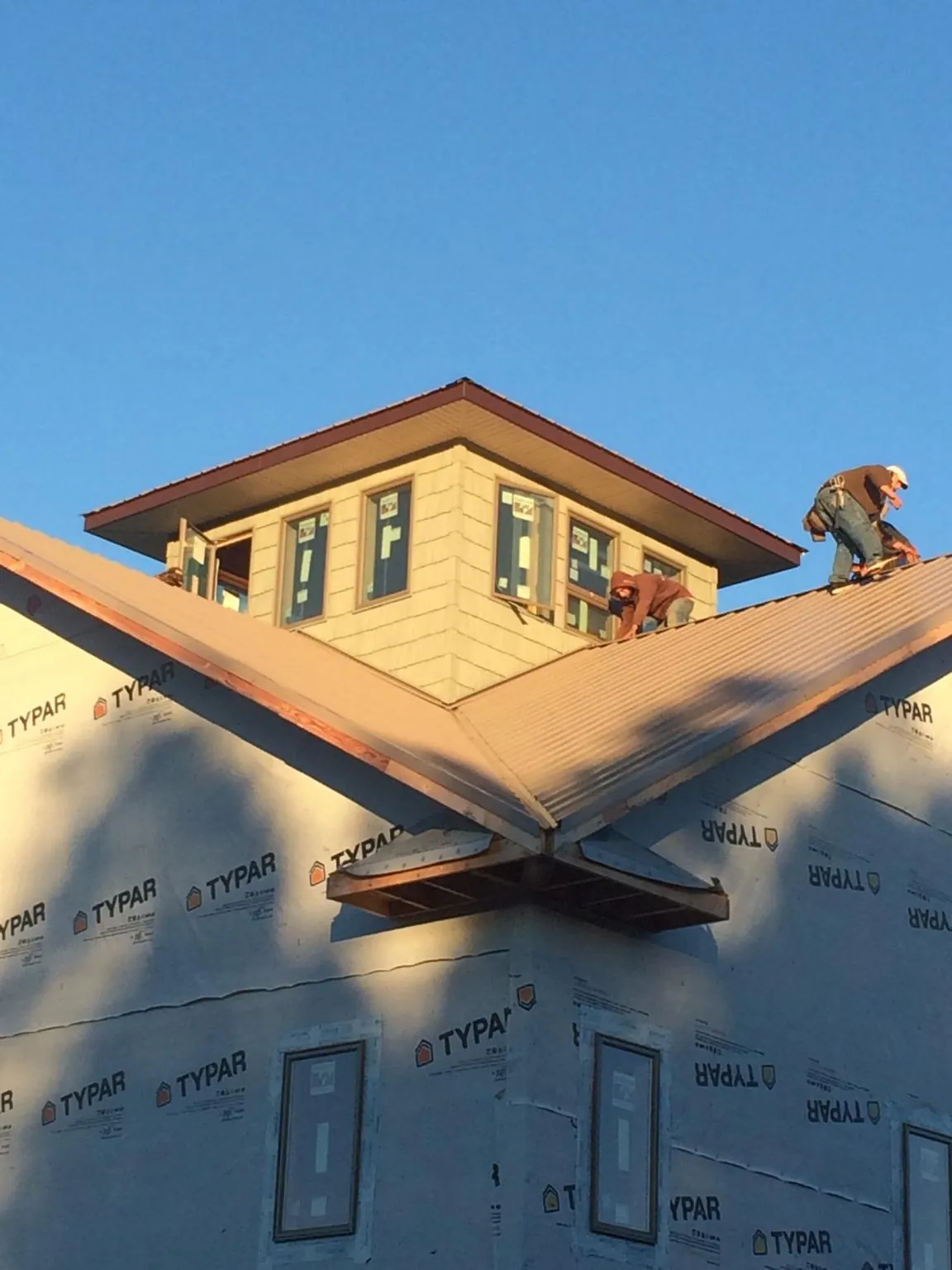 Roofers working around a rooftop cupola on a new metal roof at sunset — Roof Waterproofing in Mattaponi by Roofing Brothers